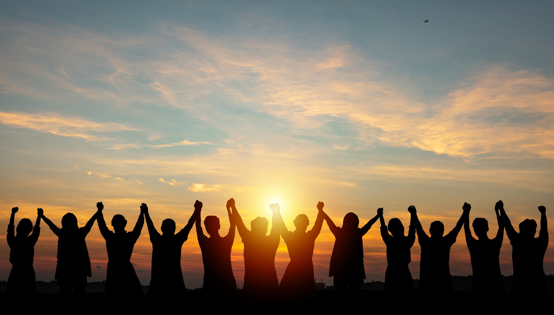 Silhouette of group business team making high hands over head in sunset sky